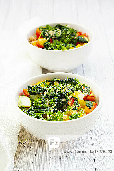 Zwei Schalen warmer veganer Quinoa-Salat mit Spinat  Paprika  Gurken  Tomaten  Petersilie und Minze