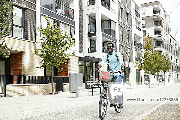 Glücklicher Mann hört Musik beim Pendeln auf dem Fahrrad in der Stadt