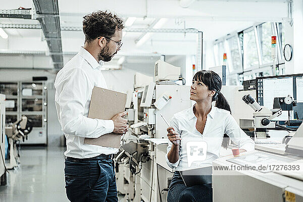 Confident female technician discussing with male colleague at laboratory