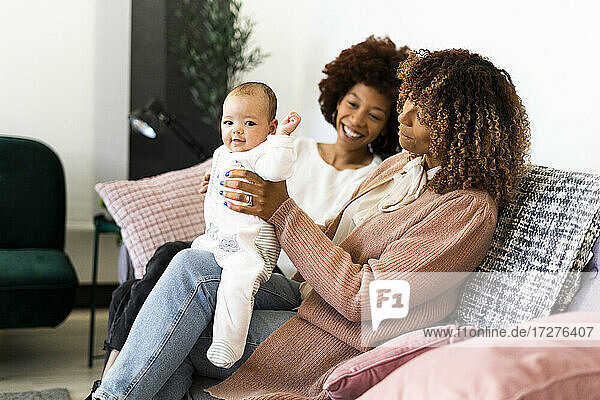 Lächelnde Familie mit einem kleinen Mädchen auf dem Sofa zu Hause
