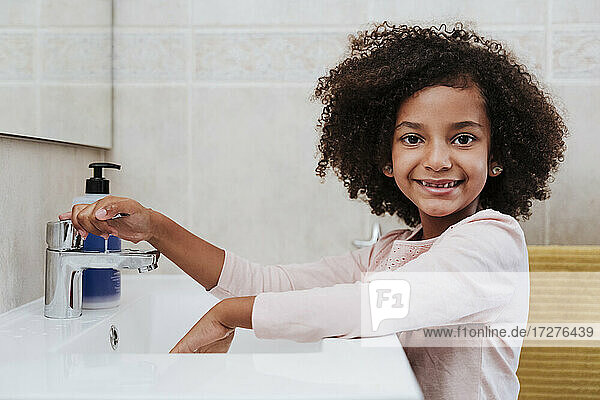 Lächelndes Mädchen beim Händewaschen zu Hause