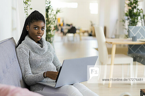 Unternehmerin arbeitet am Laptop  während sie zu Hause auf dem Sofa sitzt
