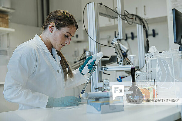 Laborant beim Pipettieren von Flüssigkeiten im Stehen im Labor