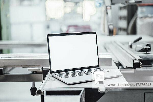 Laptop mit leerem Bildschirm an einer Maschine in einer Fabrik