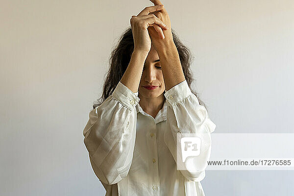 Female model posing with hands clasped against wall