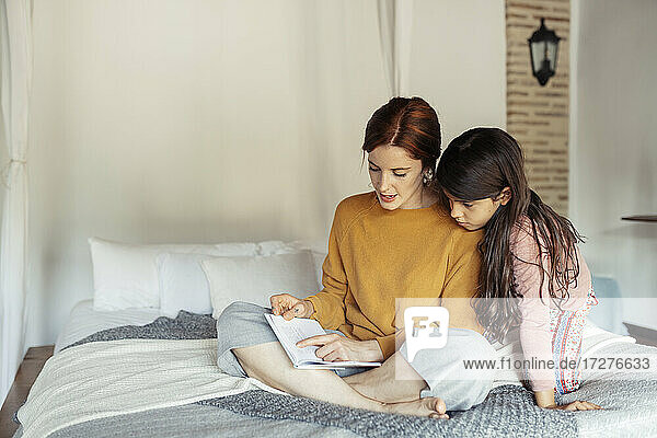 Mutter unterrichtet Tochter  während sie zu Hause auf dem Bett sitzt