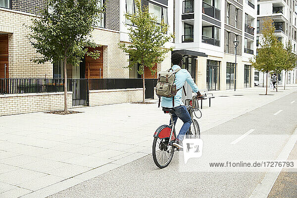 Älterer Mann mit Rucksack  der mit dem Fahrrad in der Stadt unterwegs ist