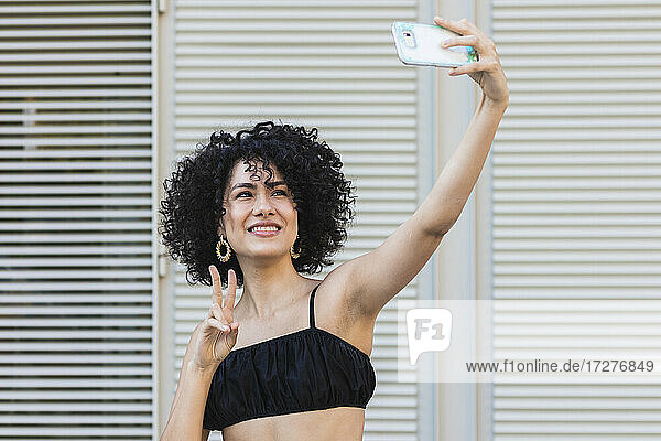 Junge Frau nimmt Selfie auf Smartphone stehend gegen Metallwand