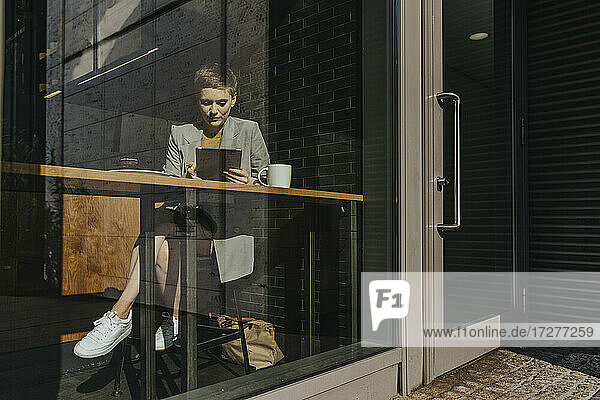 Frau hält digitale Tabelle  während sie in einem Café sitzt