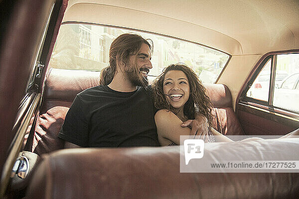 Junges Paar lacht bei der Entspannung im Auto an einem sonnigen Tag