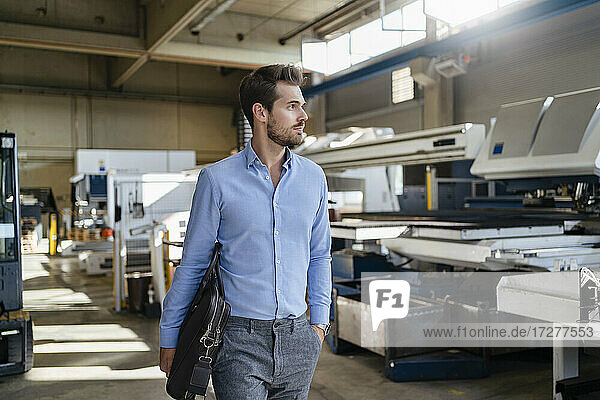 Male entrepreneur with brief case walking at factory