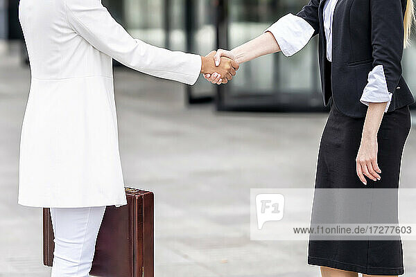 Geschäftsfrauen beim Händeschütteln auf dem Gehweg stehend