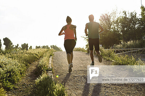 Fit junges Paar joggt im Park bei Sonnenuntergang
