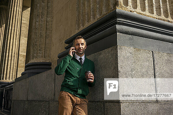 Businessman talking on mobile phone while leaning on pillar of Kazan Cathedral at Saint Petersburg  Russia