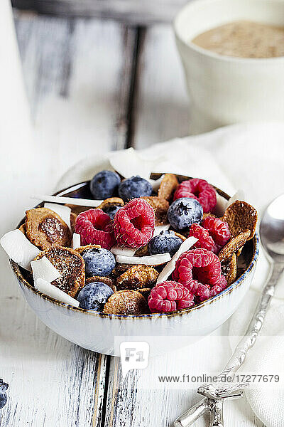 Bowl of homemade cereals with coconut  raspberries and blueberries