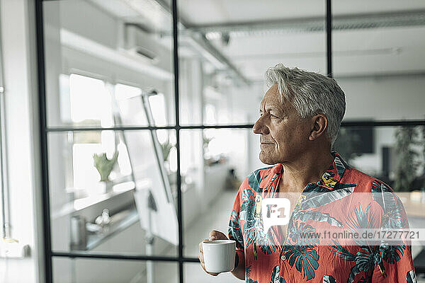 Geschäftsmann hält Kaffeetasse  während er im Büro steht