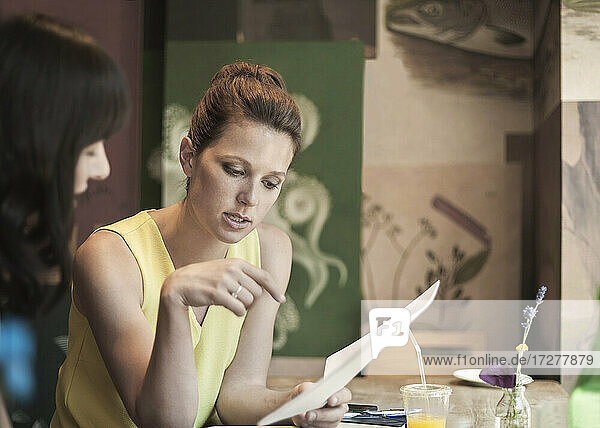 Businesswomen discussing over document during meeting in coffee shop