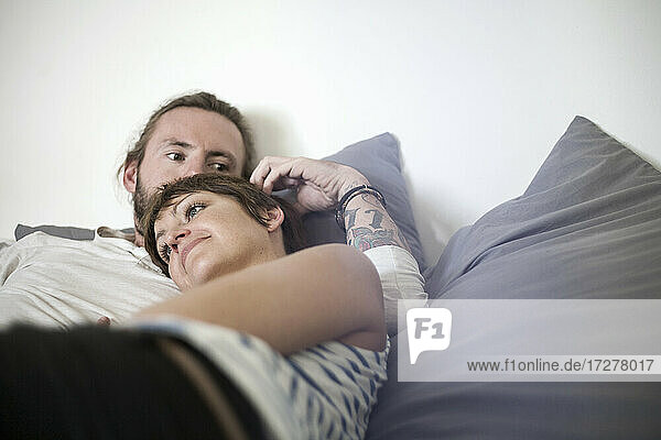 Mittlerer erwachsener Mann und junge Frau entspannen sich auf dem Bett im Schlafzimmer zu Hause