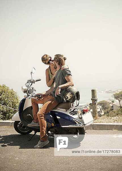 Männliche Freunde sitzen auf einem Motorrad an einem sonnigen Tag