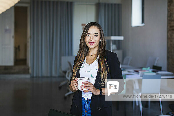 Lächelnde Geschäftsfrau mit Kaffeebecher im Büro