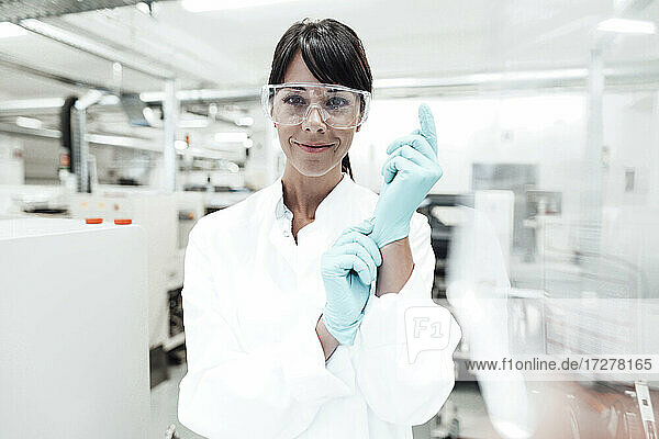 Lächelnde reife Wissenschaftlerin mit Handschuhen im Labor