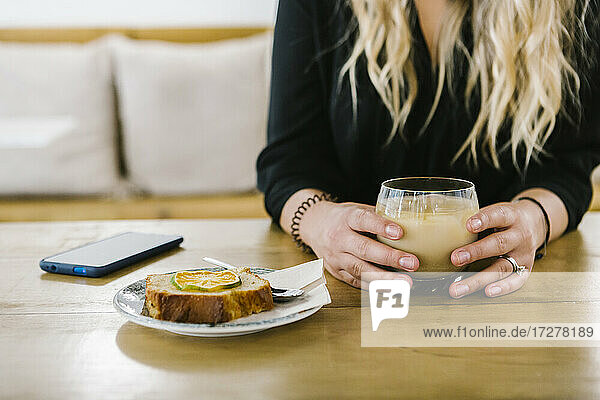 Mittlere erwachsene Frau bei Kaffee und Kuchen in einem Café sitzend