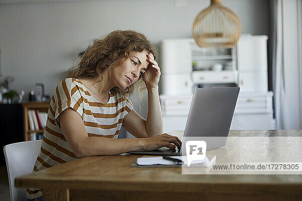 Frustrierte Frau bei der Arbeit am Laptop zu Hause