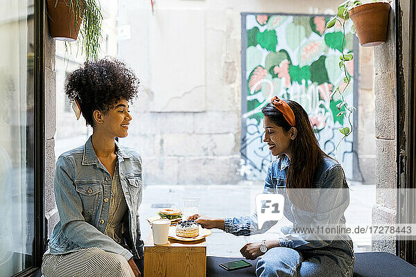 Freunde beim Essen und Trinken am Fenster eines Cafés