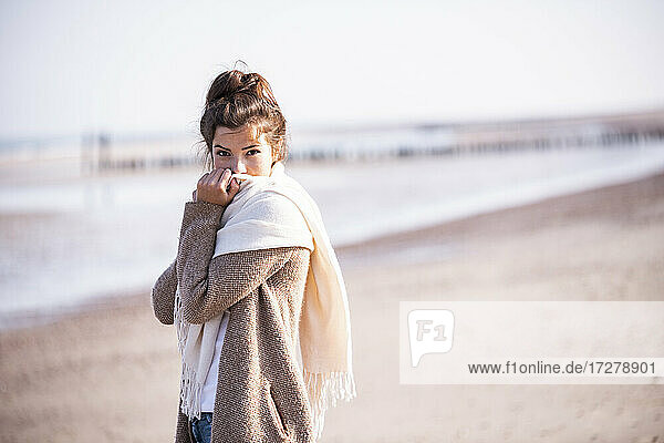 Schöne junge Frau steht am Strand an einem sonnigen Tag