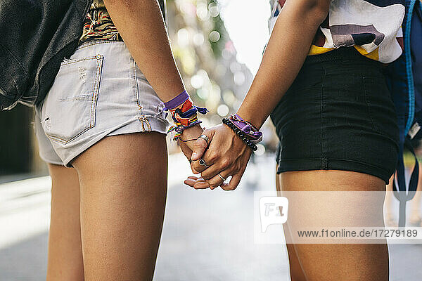 Lesbian couple holding hands standing on alley in city