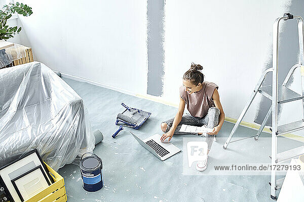 Frau mit Papier  die zu Hause sitzend am Laptop arbeitet