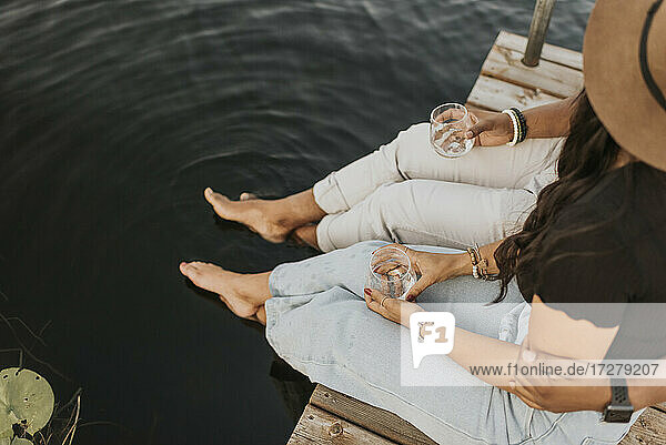 Freund und Freundin trinken Wein  während sie auf dem Pier sitzen
