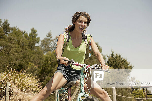 Happy young woman riding bicycle on sunny day