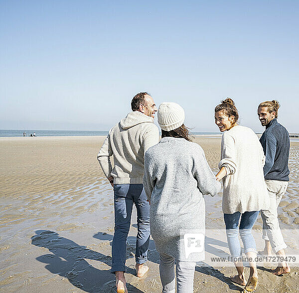 Smiling family holding hands of each other while walking at beach