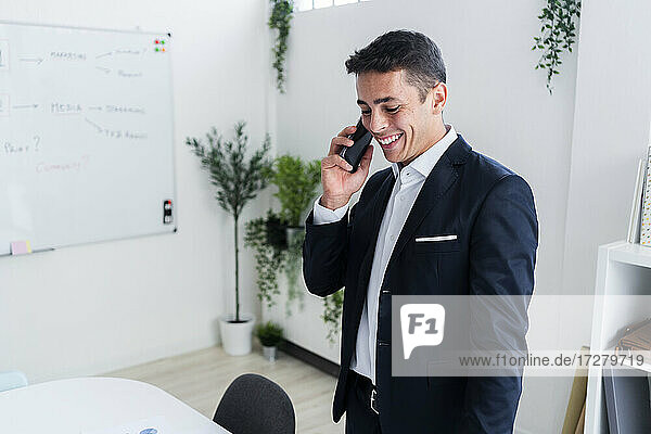 Smiling businessman talking on mobile phone while working at creative office