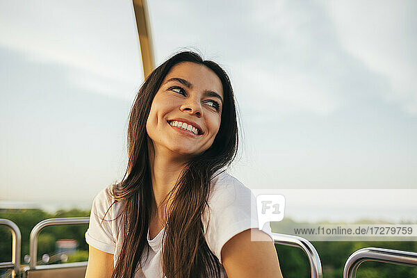 Lächelnde schöne Frau schaut weg  während sie den Sonnenuntergang vom Riesenrad aus genießt