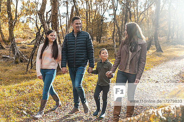 Familie  die sich gegenseitig anschaut  während sie im Herbst im Park spazieren geht