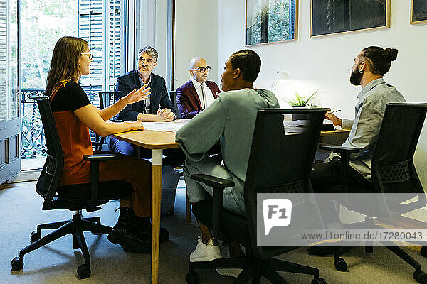 Businesswoman discussing with coworkers at table in office