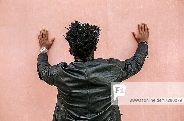 Mittlerer erwachsener Mann mit Locken  der vor einer rosa Wand steht