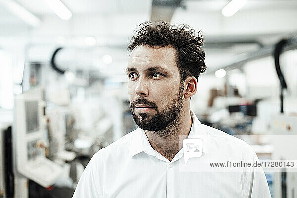 Thoughtful male professional looking away in bright industry