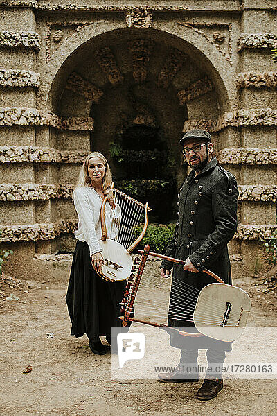 Ein Mann und eine Frau halten ein Lyra-Musikinstrument vor einem Gebäude