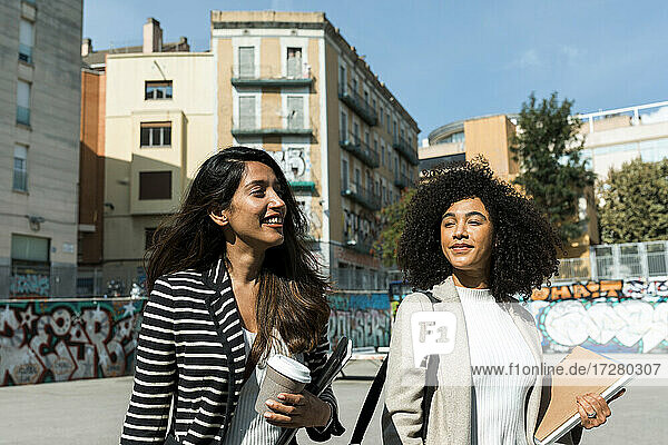 Weibliche Mitarbeiter schauen weg  während sie an einem sonnigen Tag auf der Straße in der Stadt stehen