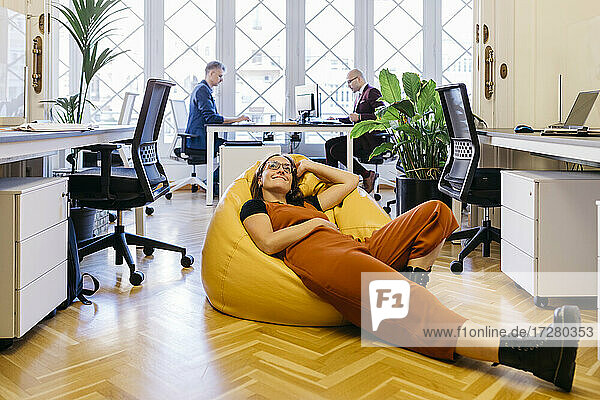 Smiling businesswoman resting on bean bag in office
