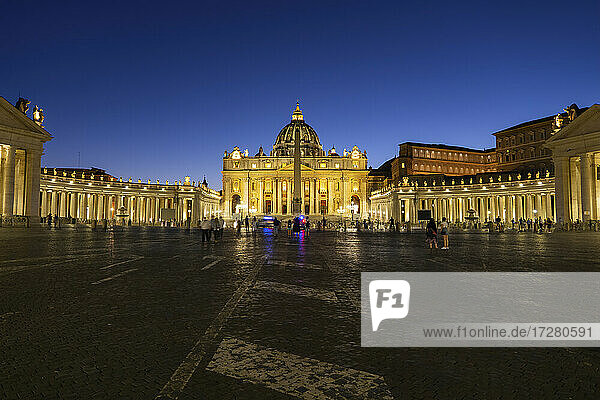 Touristen auf dem beleuchteten Petersplatz mit dem Petersdom bei klarem blauem Himmel in der Nacht  Vatikanstadt  Rom  Italien