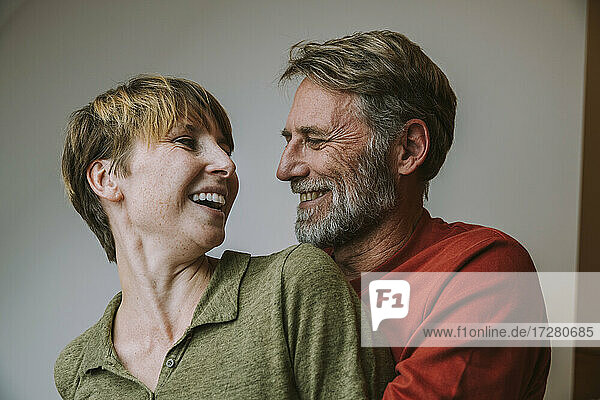 Lächelndes Paar  das sich umarmt  während es zu Hause steht