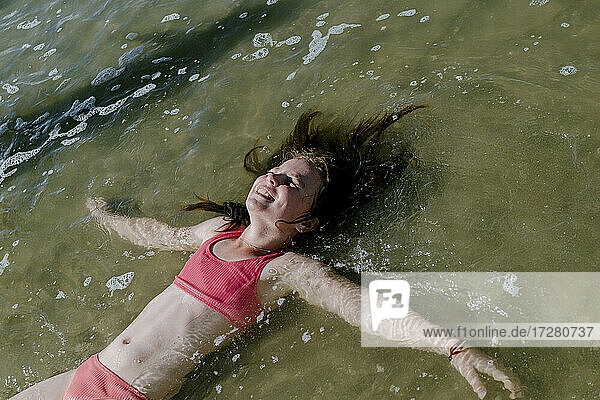 Mädchen liegt im Wasser am Strand an einem sonnigen Tag
