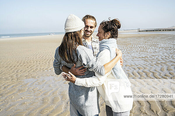 Ehepaar und Mutter stehen mit Arm um am Strand