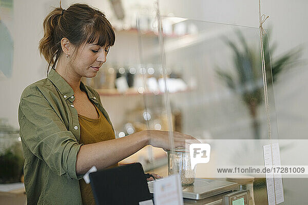 Geschäftsfrau wiegt Körner auf einer Waage in einem Cafe