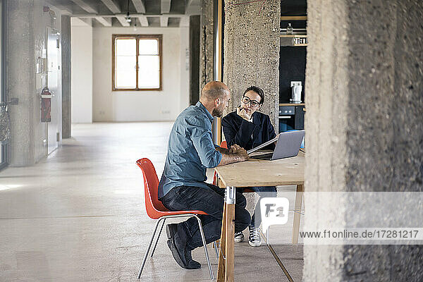 Geschäftsmann und Frau diskutieren bei der Benutzung eines Laptops im Büro