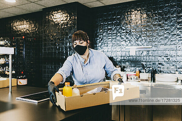 Weibliche Köchin trägt Pappkarton an der Theke in der Restaurantküche